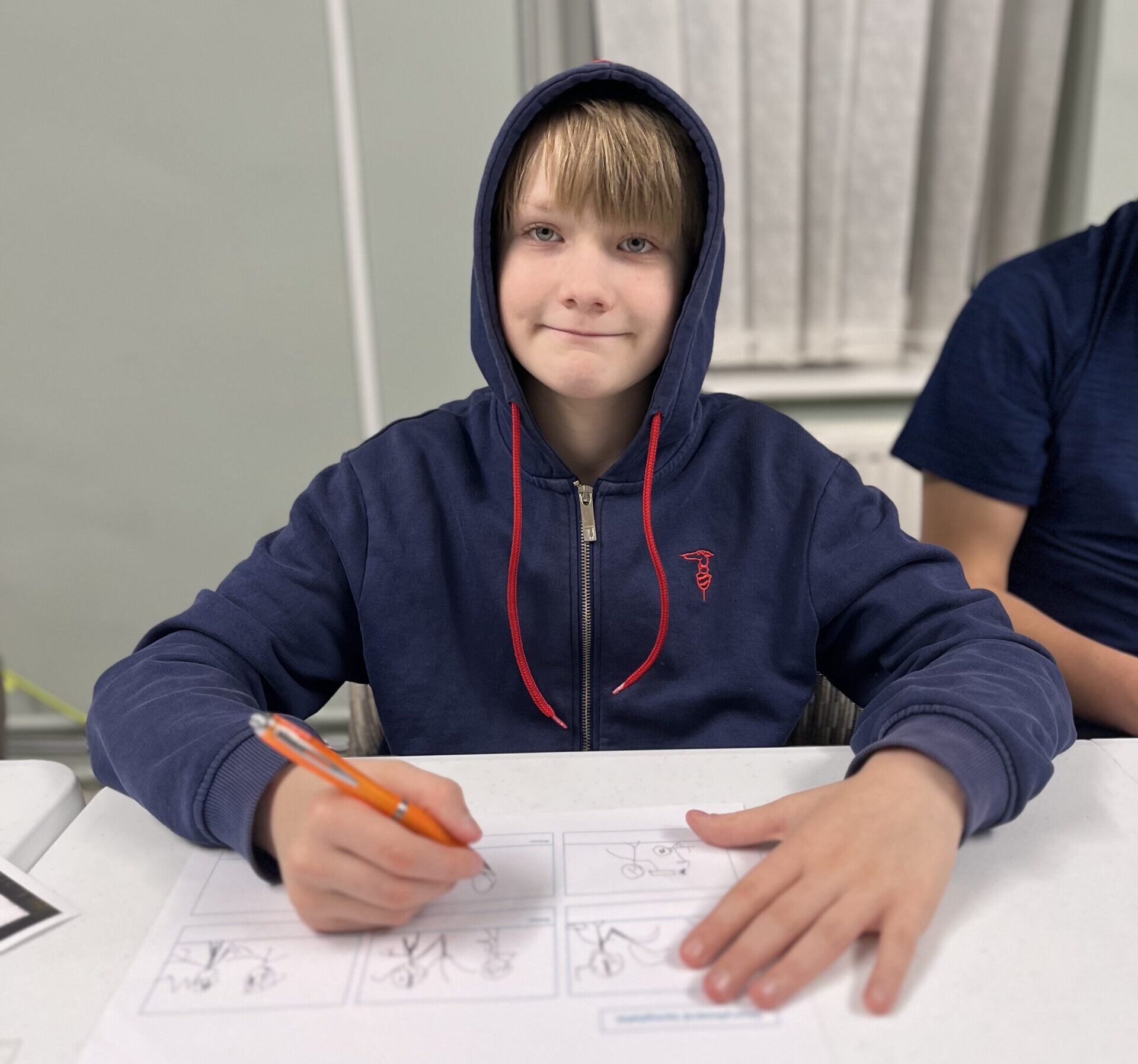 A classroom of adult students seated at laptops, with tutor Mariam at the front presenting photo editing information on a large screen.